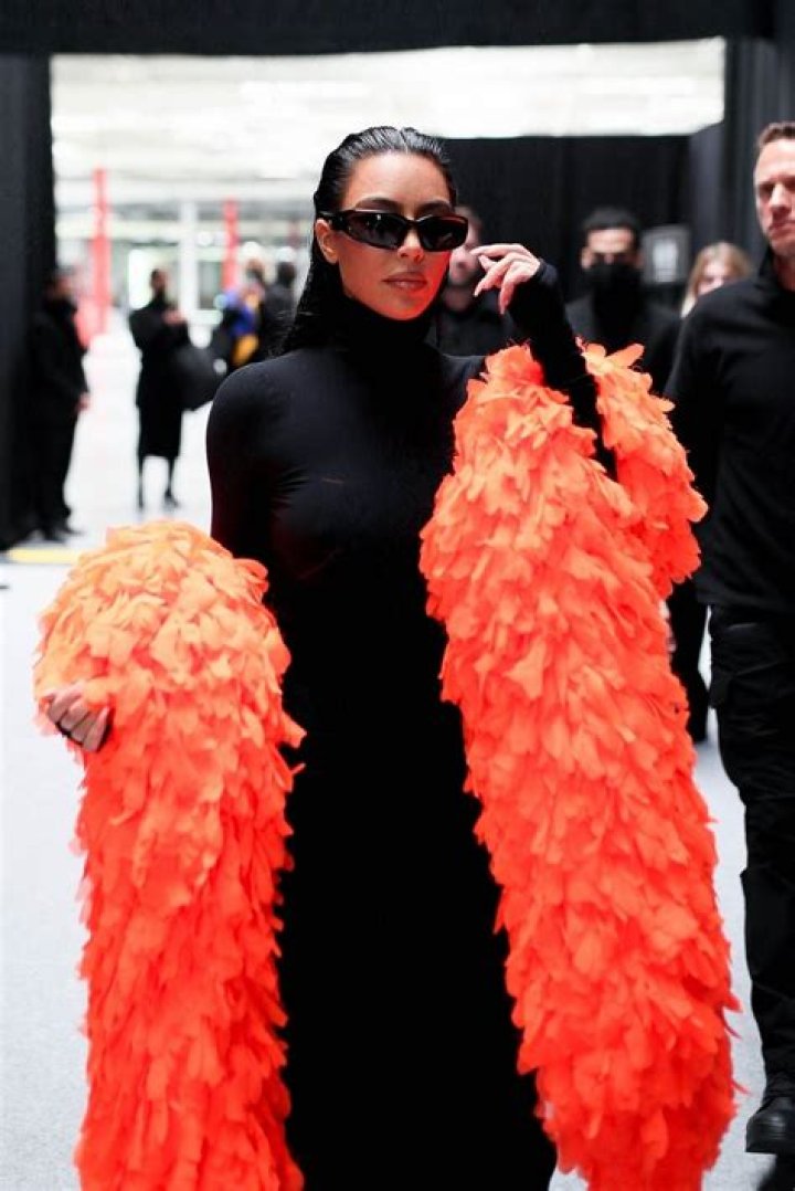 Kim Kardashian Jets Out Of Paris In Orange Feather Boa & Black Dress After Balenciaga Show